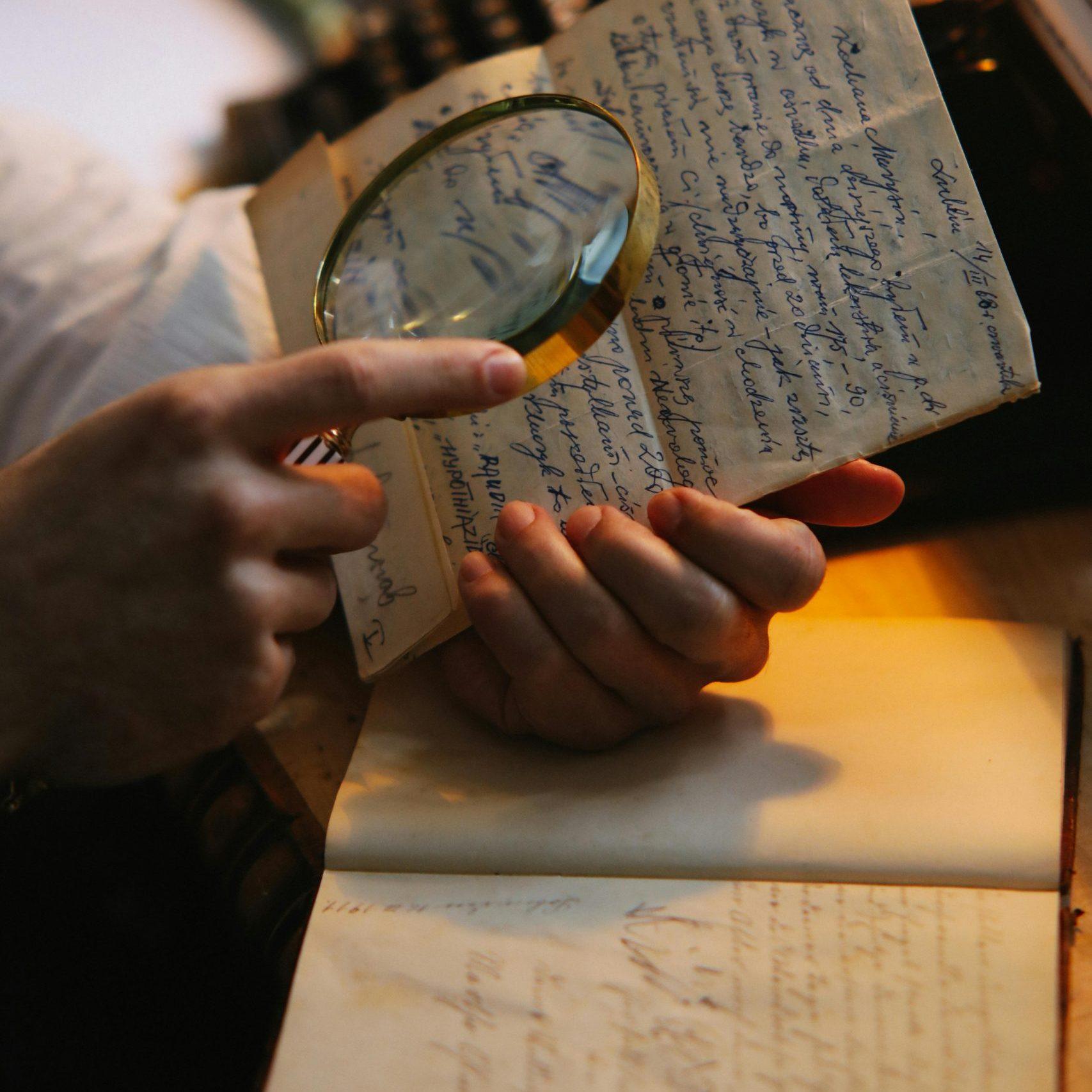 Person liest Brief mit Lupe